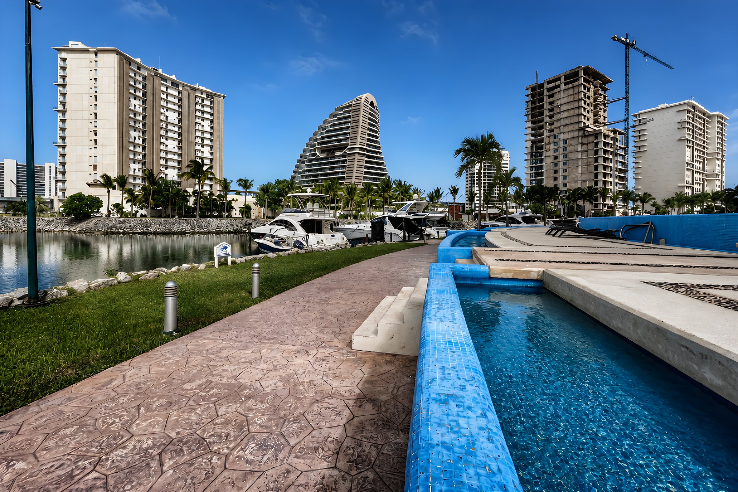 Alberca y paseo frente a la marina y las torres de Puerto Cancún en Maioris Marina Residences