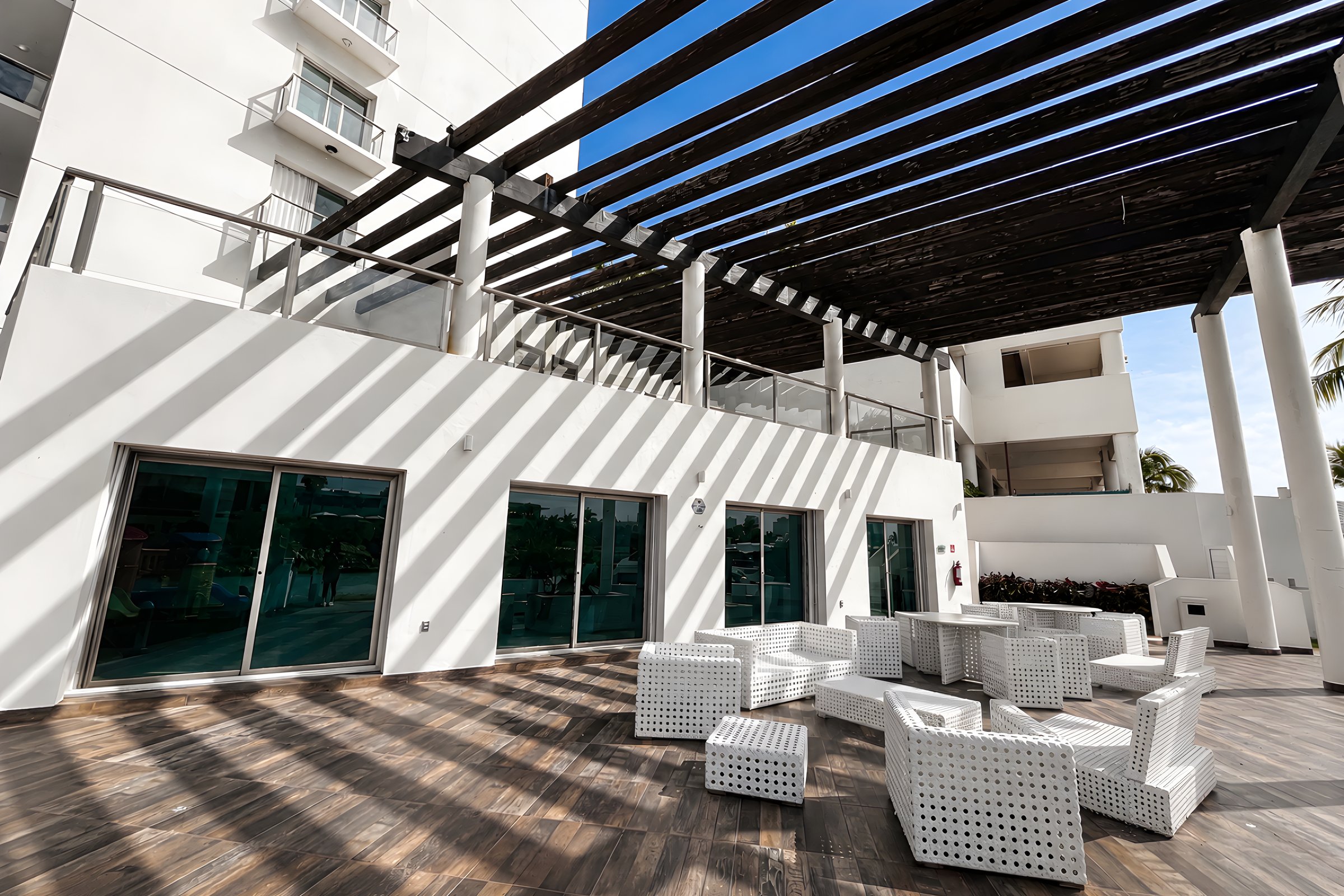 Deck social de madera bajo pérgola en Maioris Marina Residences, Puerto Cancún