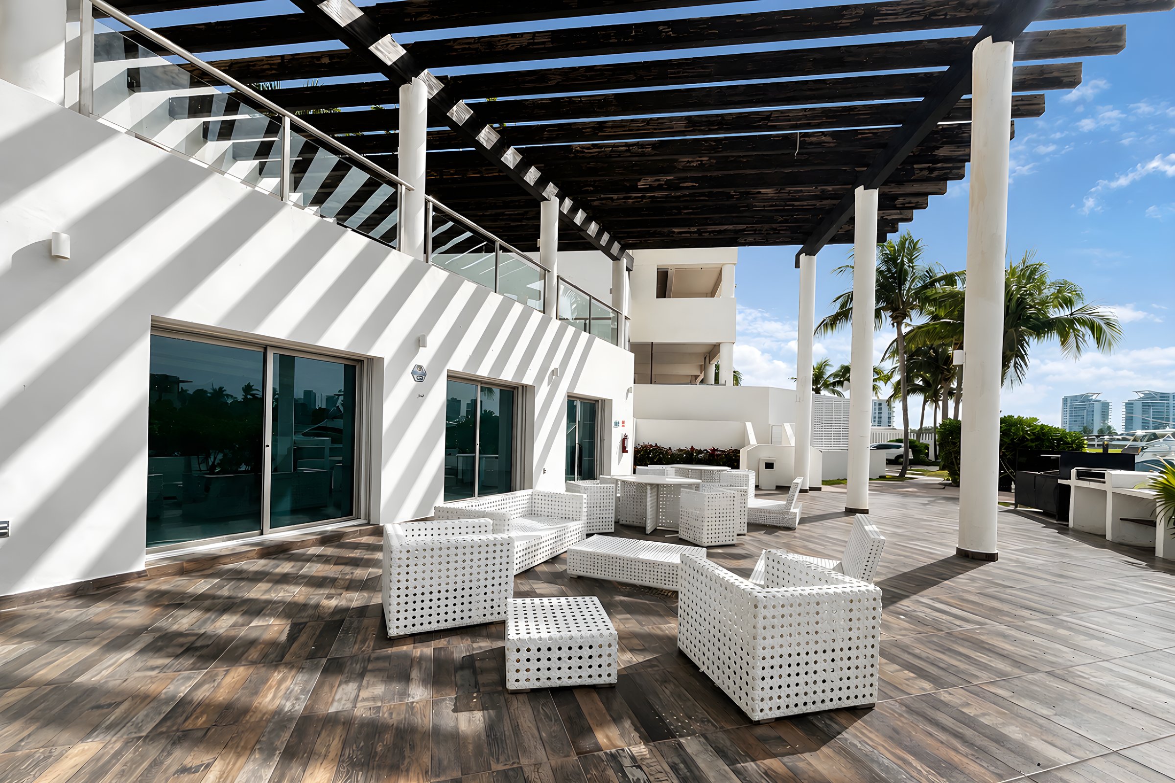 Terraza social con pérgola y sillería blanca en Maioris Marina Residences, Puerto Cancún