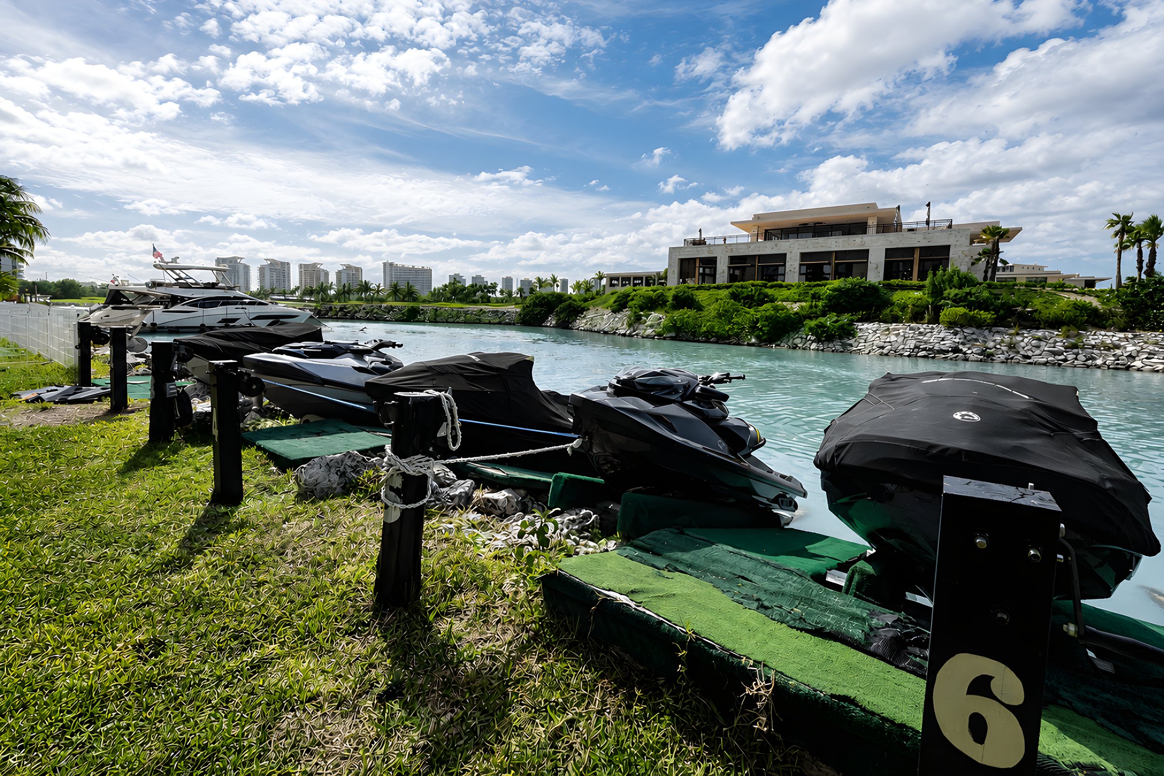 Muelle de waverunners sobre el césped junto al canal en Maioris Marina Residences, Puerto Cancún